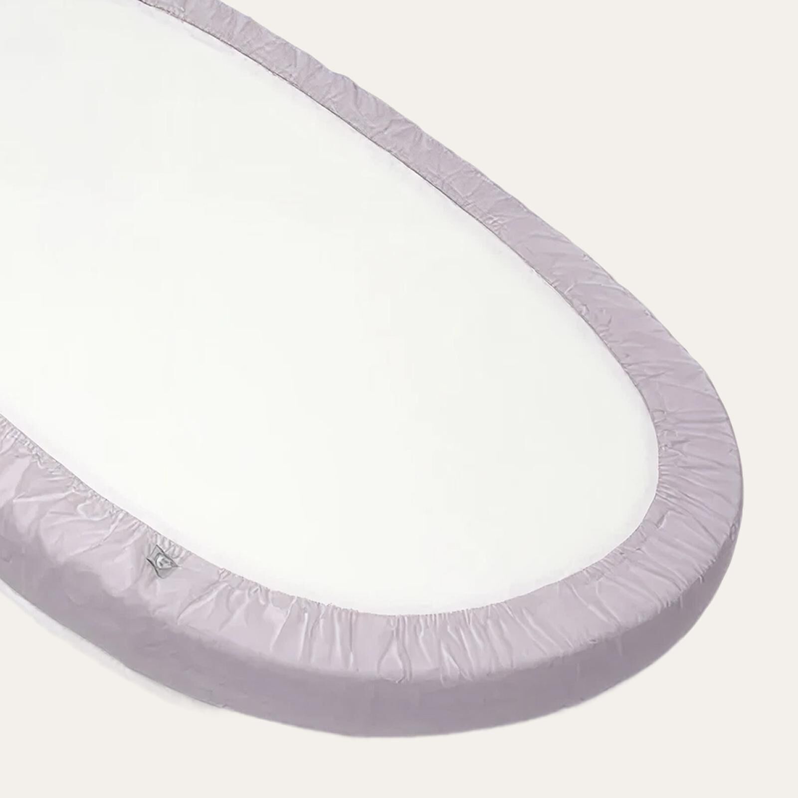 Matelas ovale Stokke Sleepi avec un drap-housse violet clair.