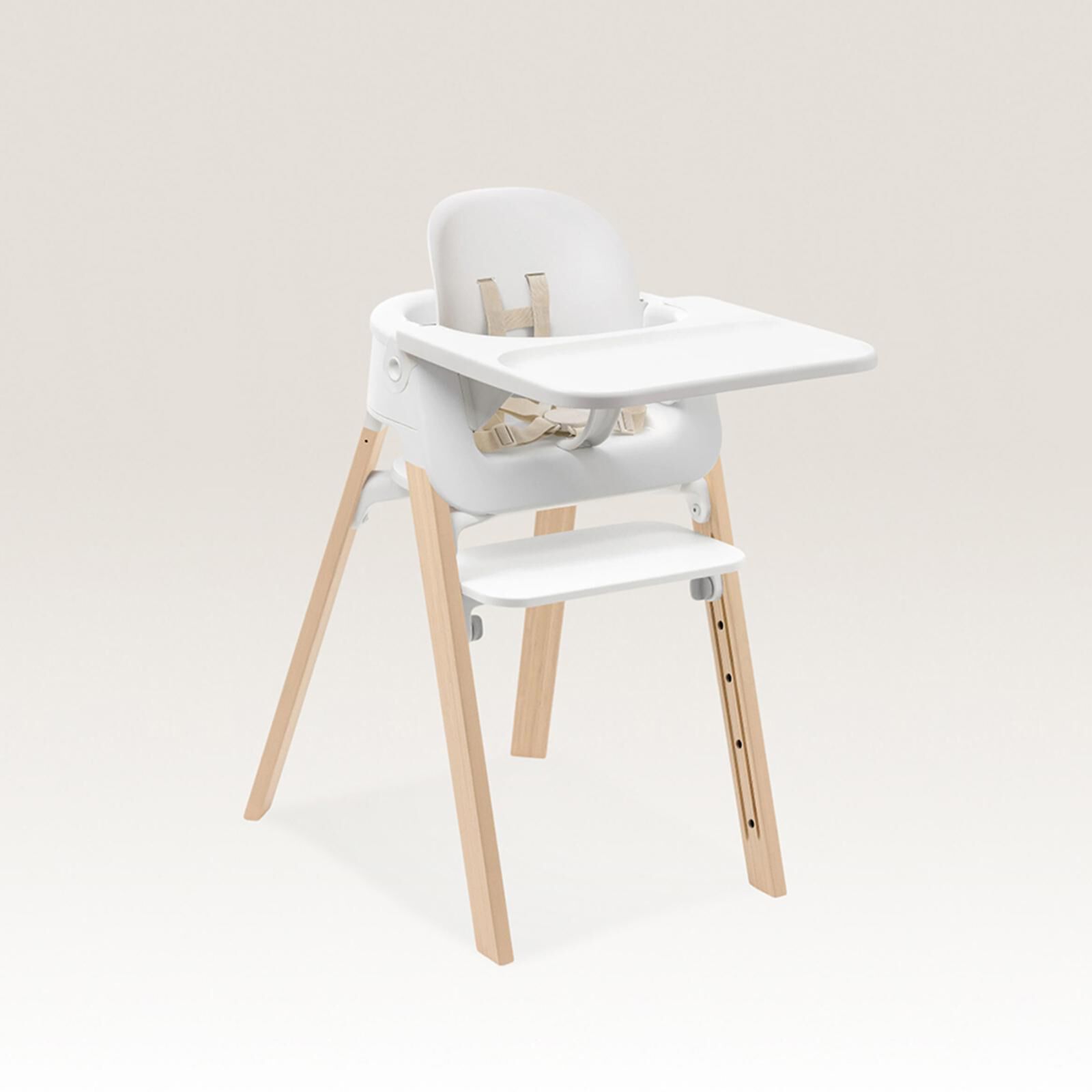 Seggiolone bianco con gambe in legno, vassoio e imbracatura di sicurezza.