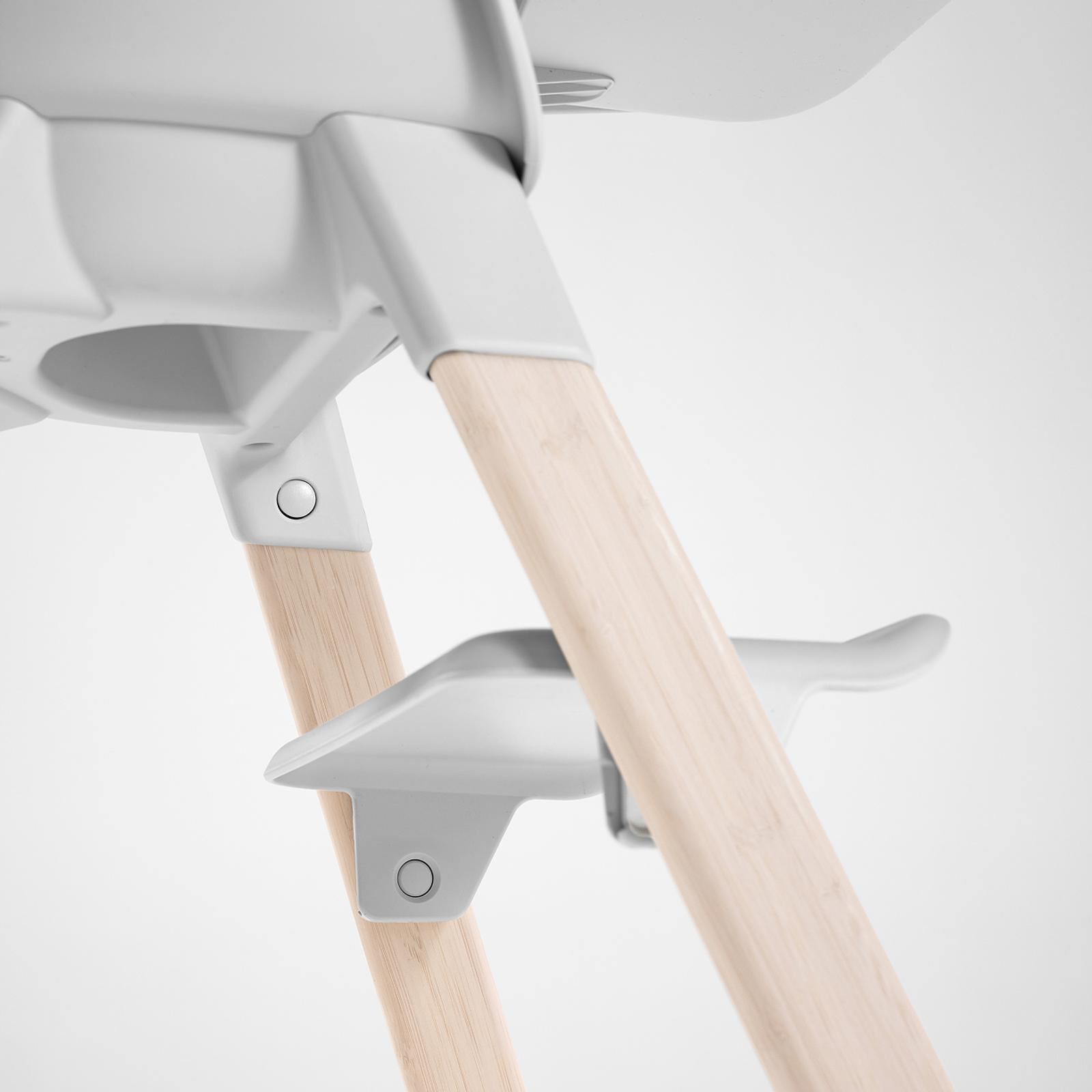 Close-up of a Tripp Trapp high chair with natural wooden legs and white components.