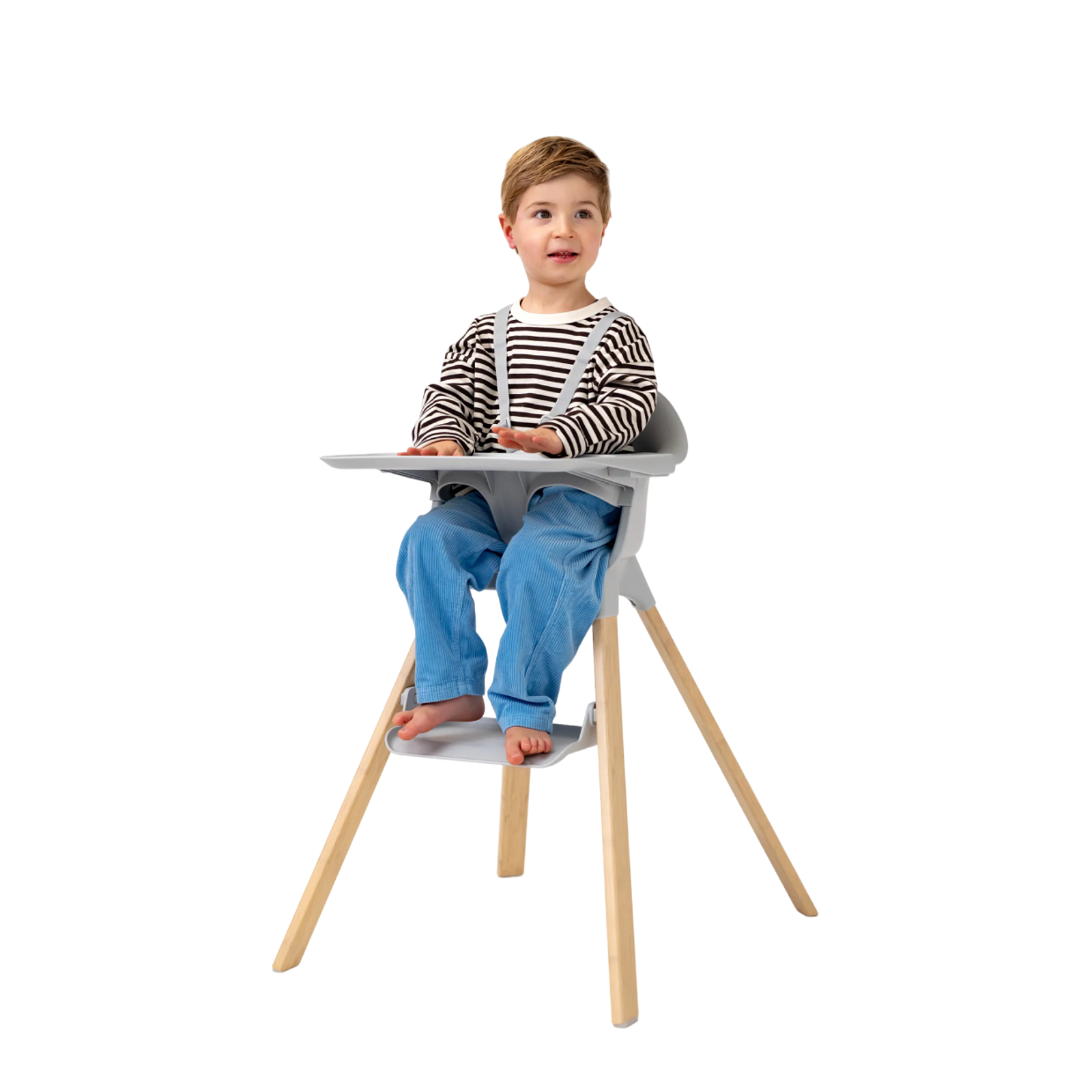 A child sits in a grey high chair with wooden legs and a tray.