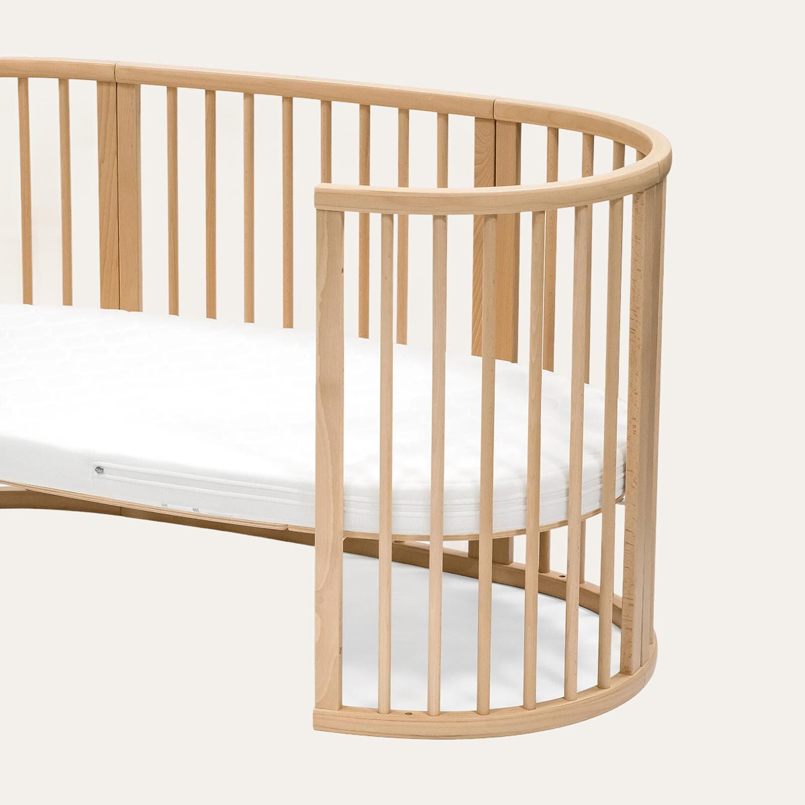 A light wood STOKKE Sleepi crib with a white mattress.