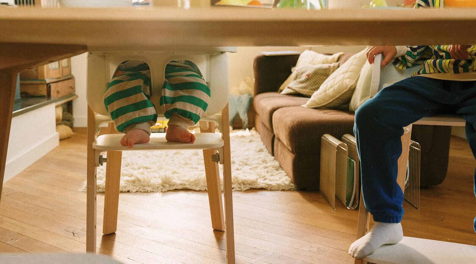 Deux enfants sont assis à une table sur des chaises Tripp Trapp, l'un dans une chaise haute Tripp Trapp.