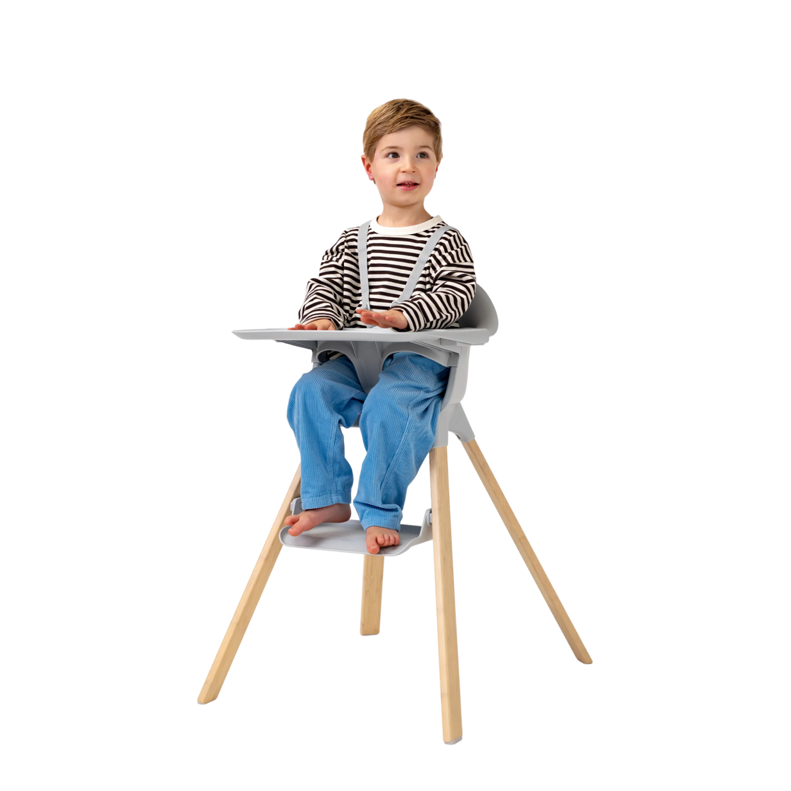 A child sits in a grey high chair with wooden legs and a tray.