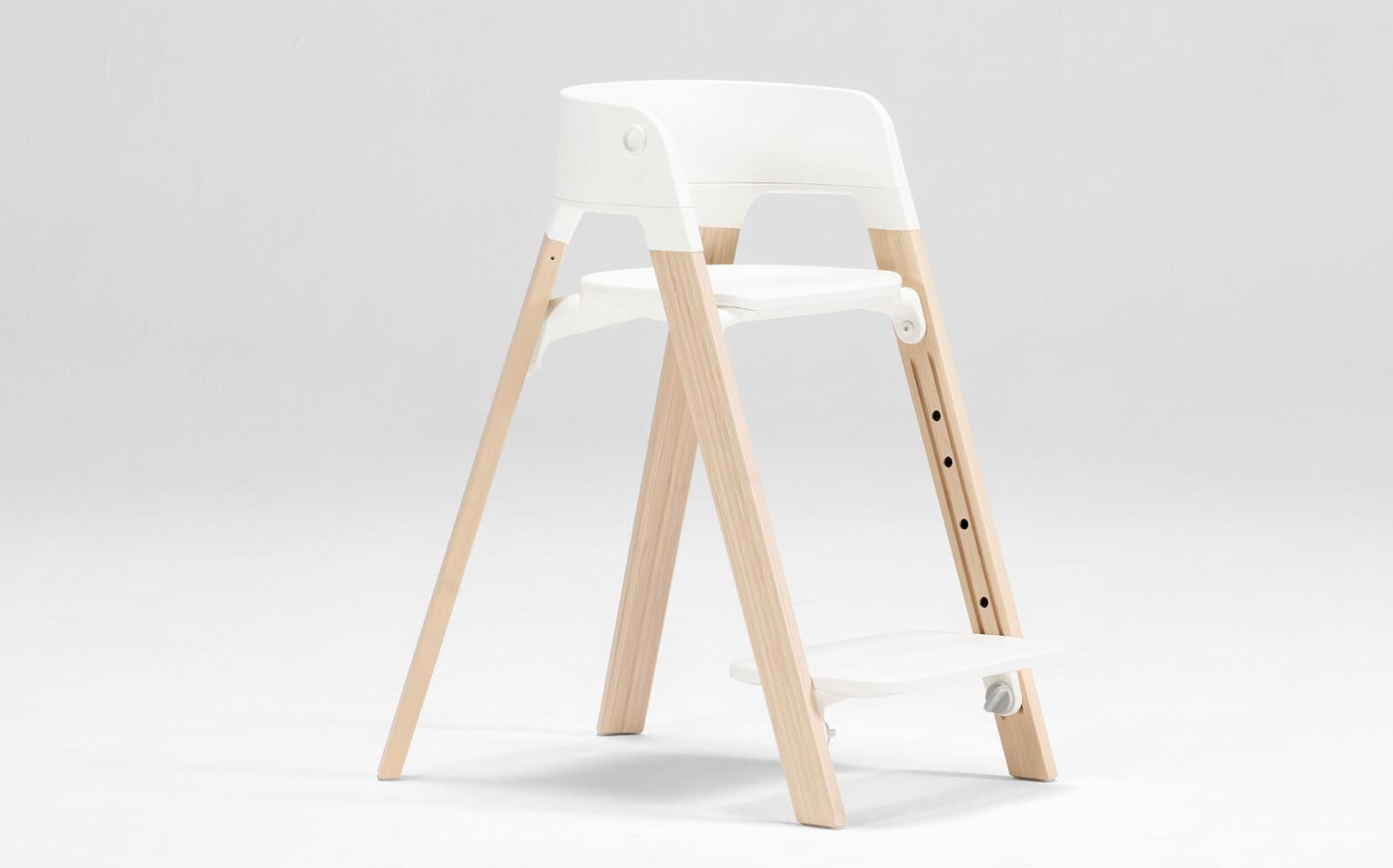 Un seggiolone bianco con gambe in legno chiaro su uno sfondo bianco pulito.
