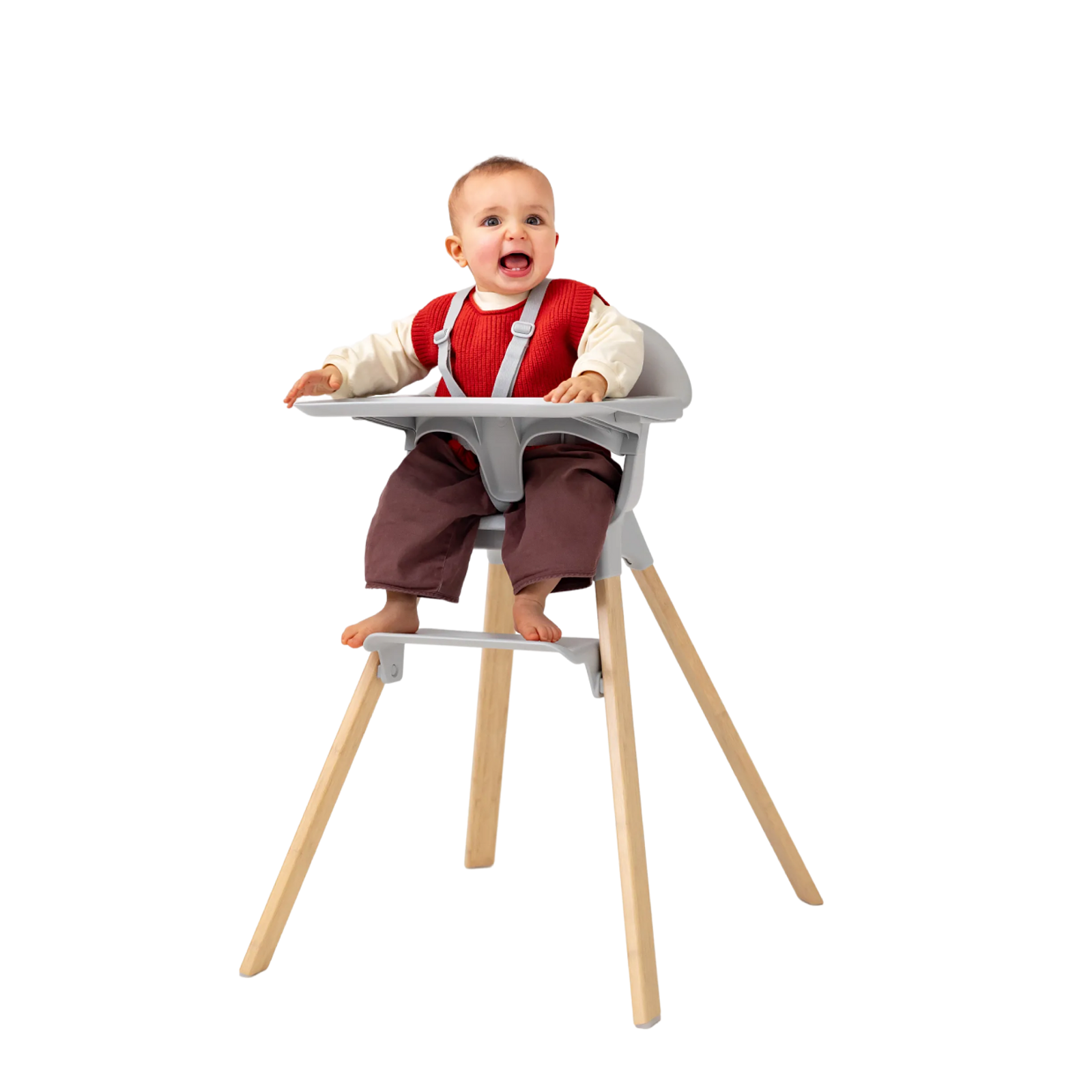 A happy baby in a gray high chair with wooden legs, smiling and looking up.
