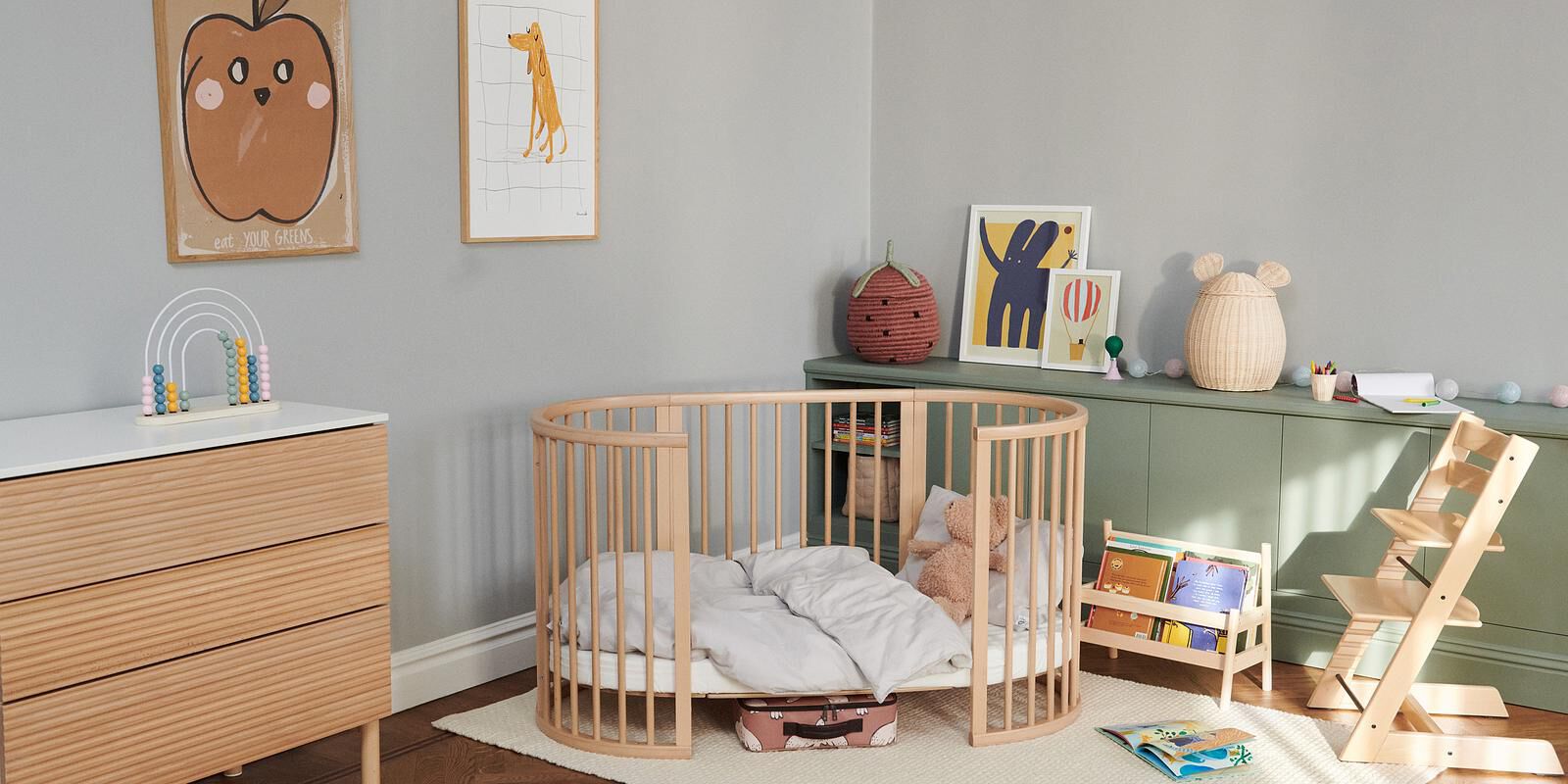 Une chambre d'enfant avec un lit bébé STOKKE Sleepi, une commode en bois et une chaise Tripp Trapp.