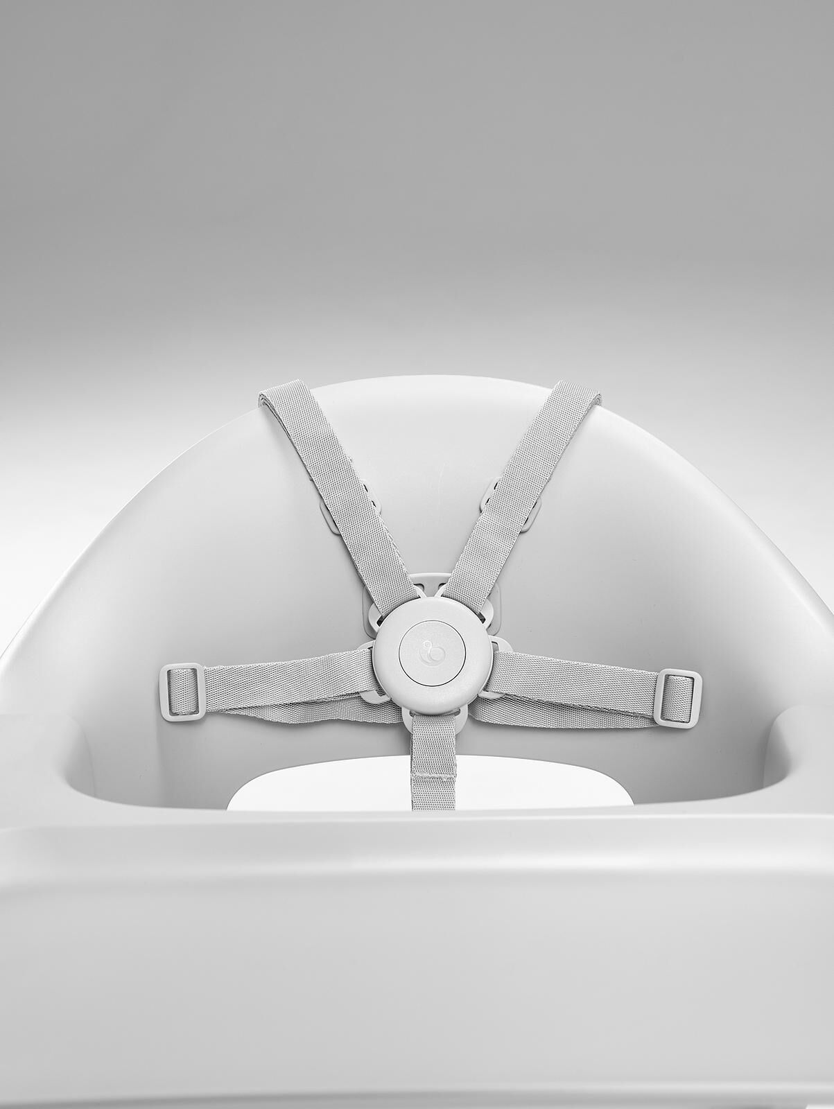 Primer plano de un asiento blanco de trona para bebé con un arnés gris de 5 puntos.