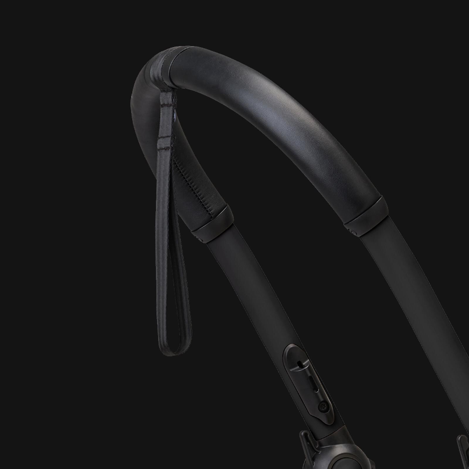 Närbild av ett svart vadderat handtag och handledsrem på en STOKKE YOYO barnvagn.