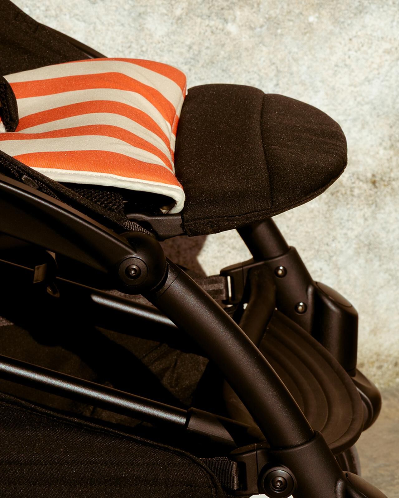 STOKKE YOYO stroller with an orange and white striped cushion.