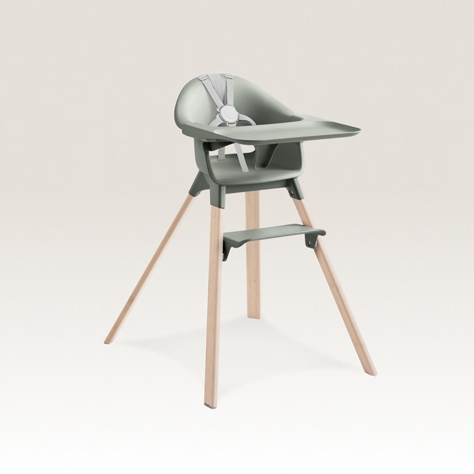 Une chaise haute moderne vert sauge avec un plateau, un harnais de sécurité et des pieds en bois évasés.