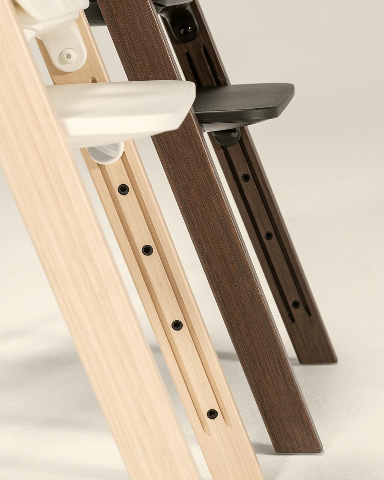 Three wooden Tripp Trapp high chairs in light, medium, and dark finishes.