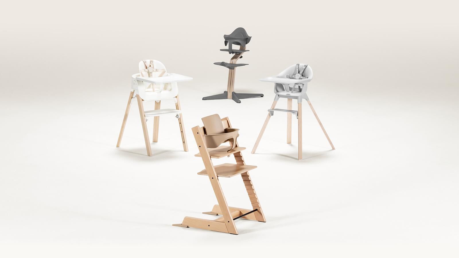 Vier kinderstoelen: een natuurlijke Tripp Trapp met Baby Set, een witte, een lichtgrijze en een donkergrijze.