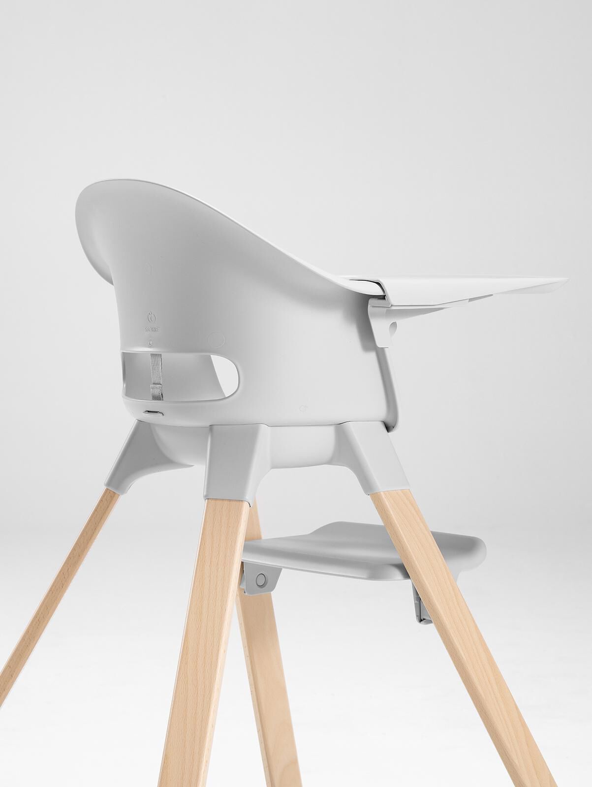 A grey STOKKE high chair with wooden legs and a tray.