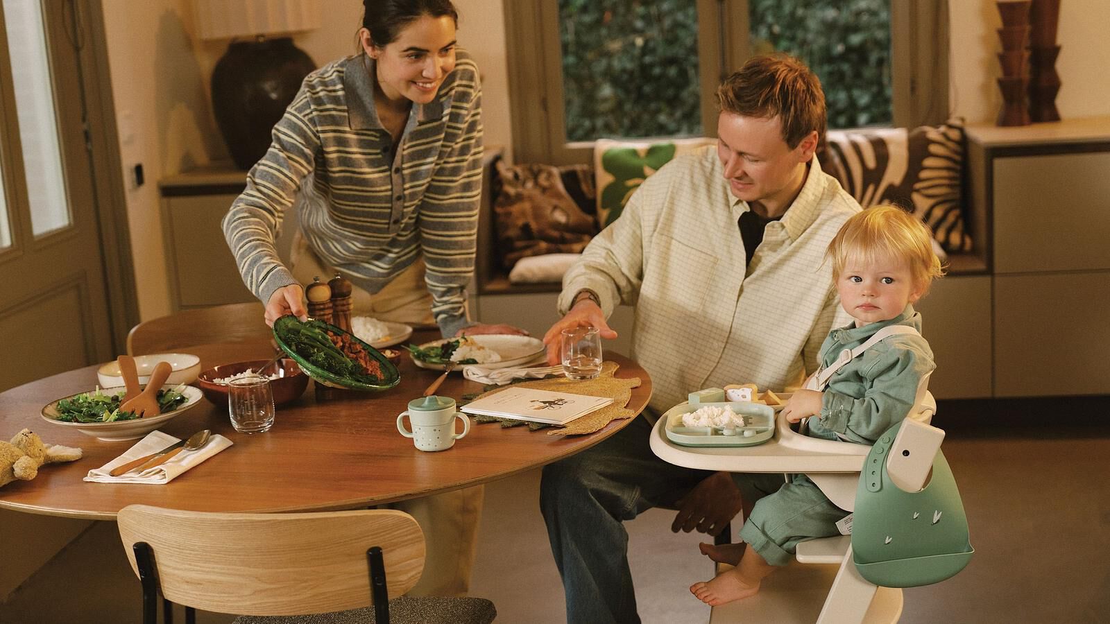 yoyo_hero-image_desktop_jpg Een gezin aan het diner, mama serveert, baby in een Tripp Trapp kinderstoel kijkt in de camera.
