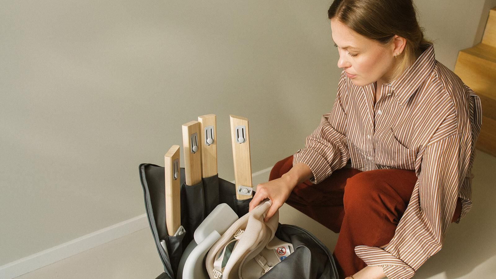 Woman packing a Tripp Trapp high chair into its travel bag.