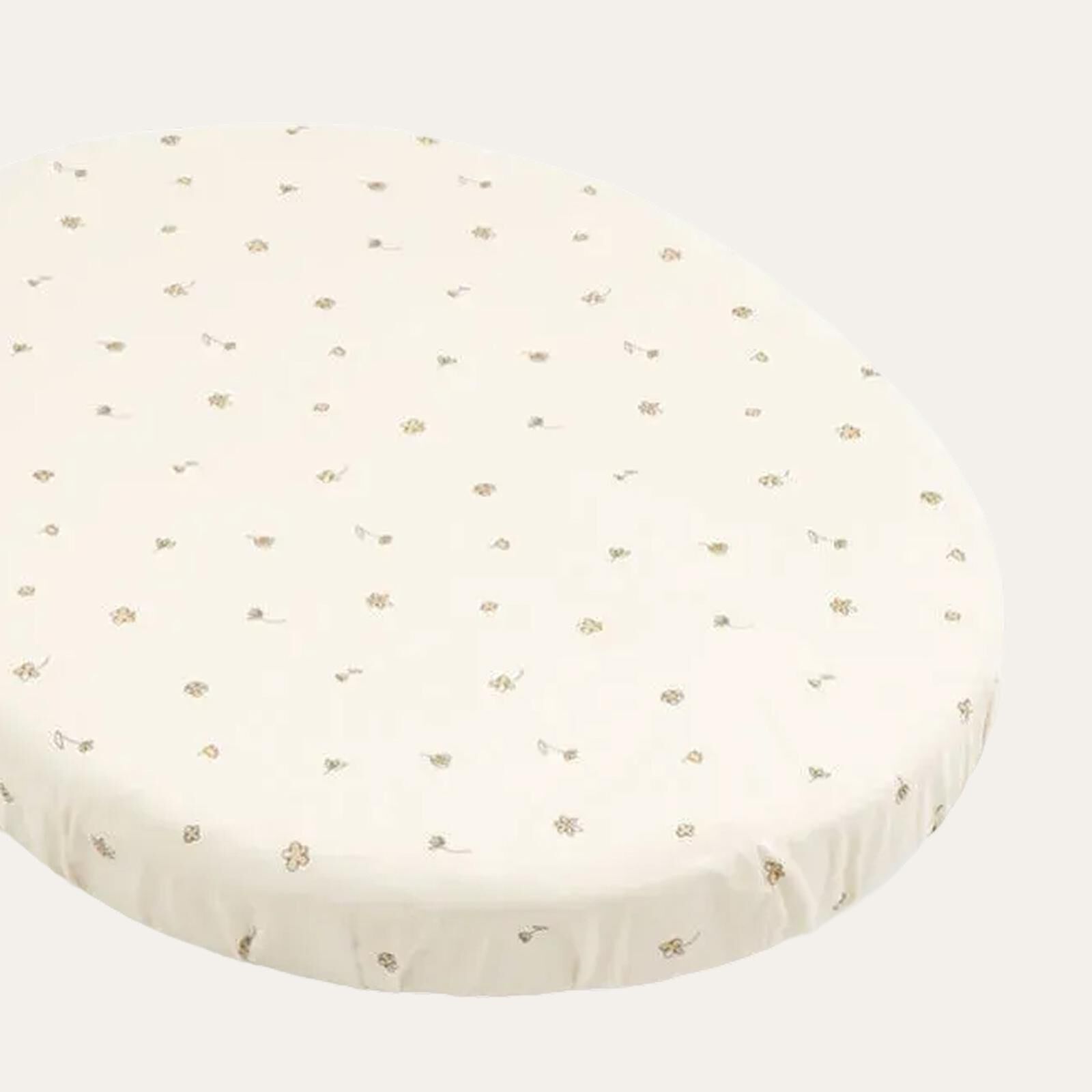 An oval cream fitted sheet with a delicate floral pattern.