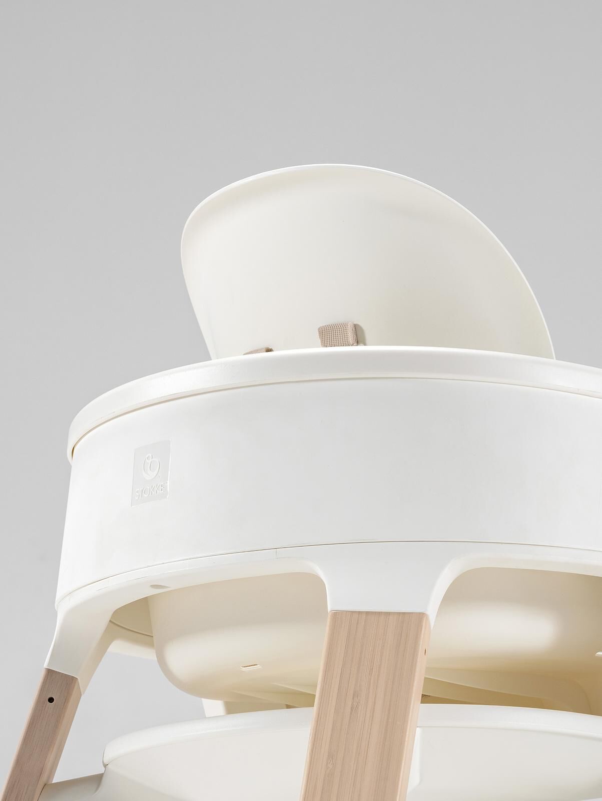 A white high chair with light wooden legs.