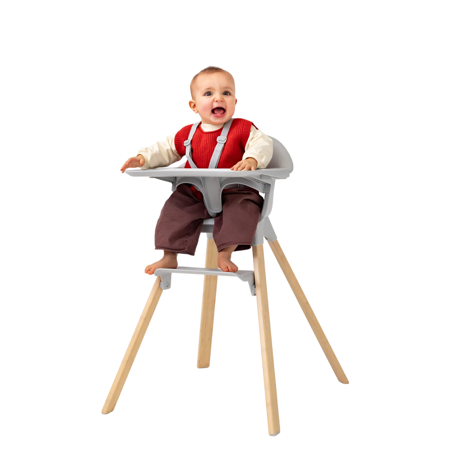 En glad baby i en grå barnestol med treben, smiler og ser opp.