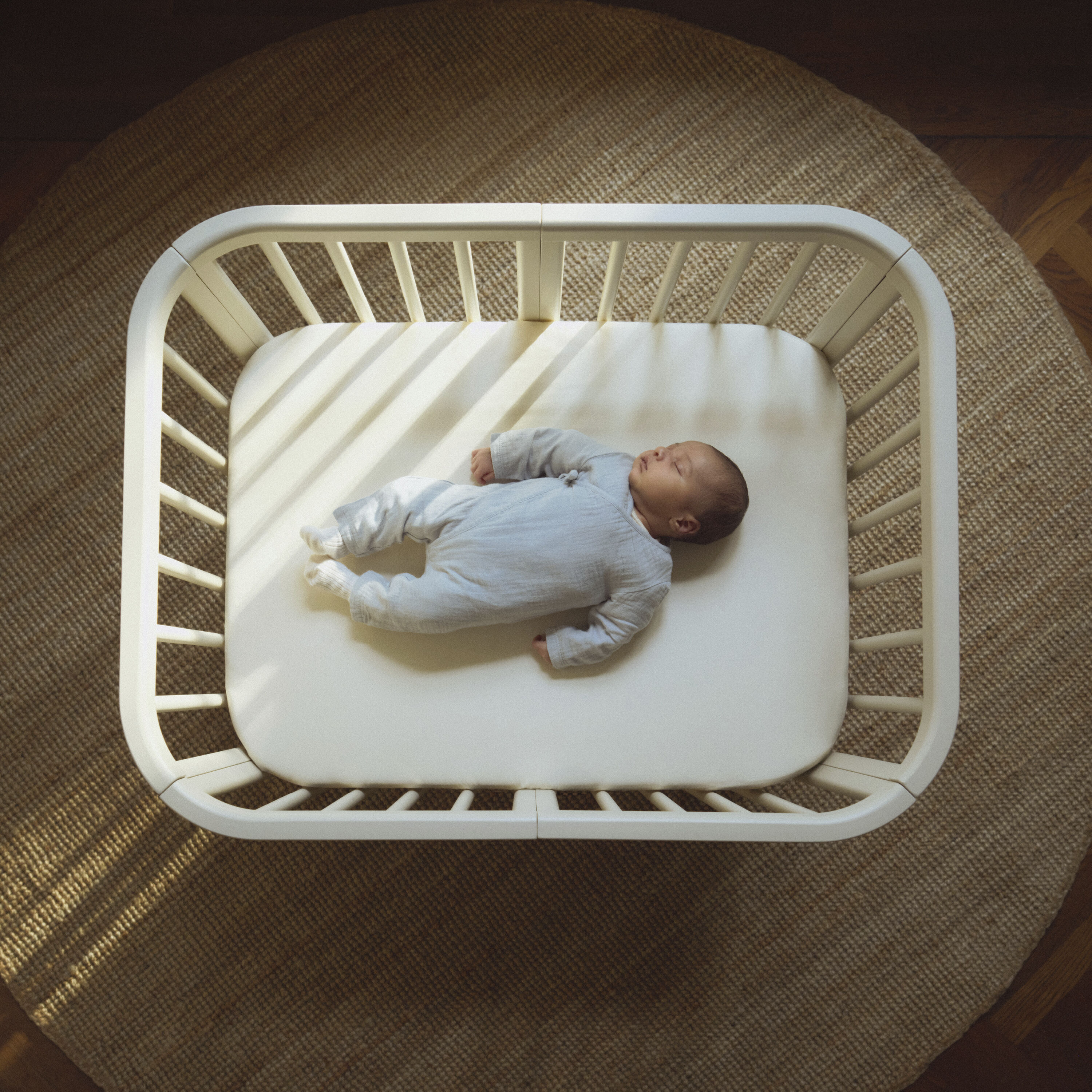 Close-up of the Stokke® Nighti™ cot bed interior with only a firm mattress and snugly fitted sheet — illustrating a clear, safe and uncluttered newborn sleep space.