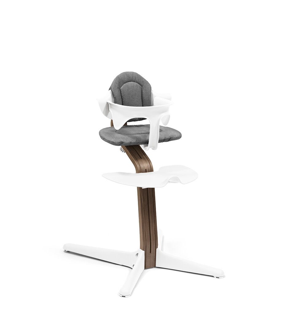 Stokke® Nomi® Chair. Premium Walnut wood and White plastic parts. With Baby Set Grey and Cushion White.