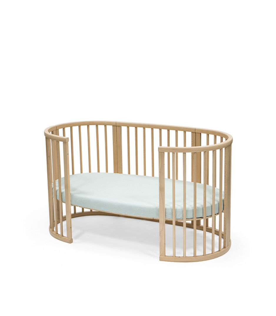 Stokke® Sleepi™ Bed, Natural. With Mattress and Fitted Sheet Dots Sage. Open.