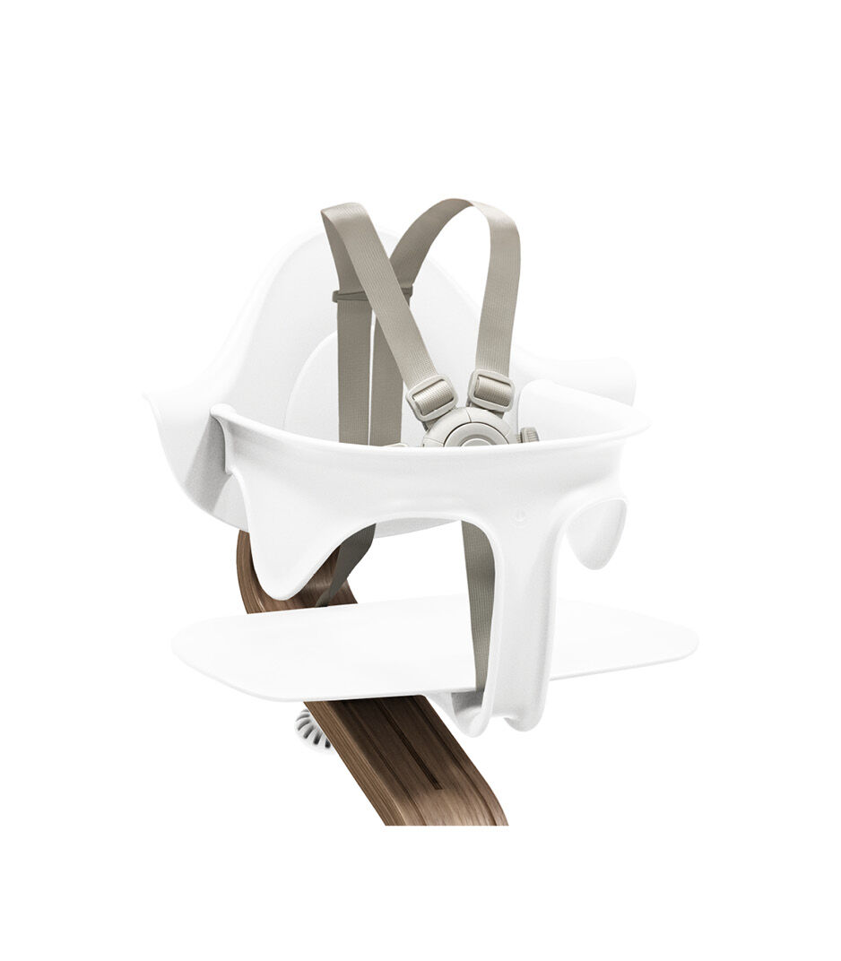 Stokke® Nomi® Chair. Premium Walnut wood and White plastic parts. With Baby Set White. US variant w/Harness. Close-up.