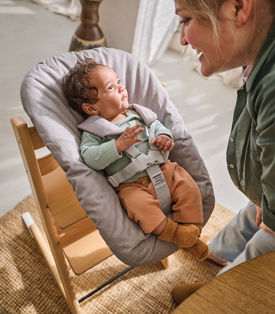 Tripp Trapp® Chair Natural with Newborn Set Grey. Around the table close-up.