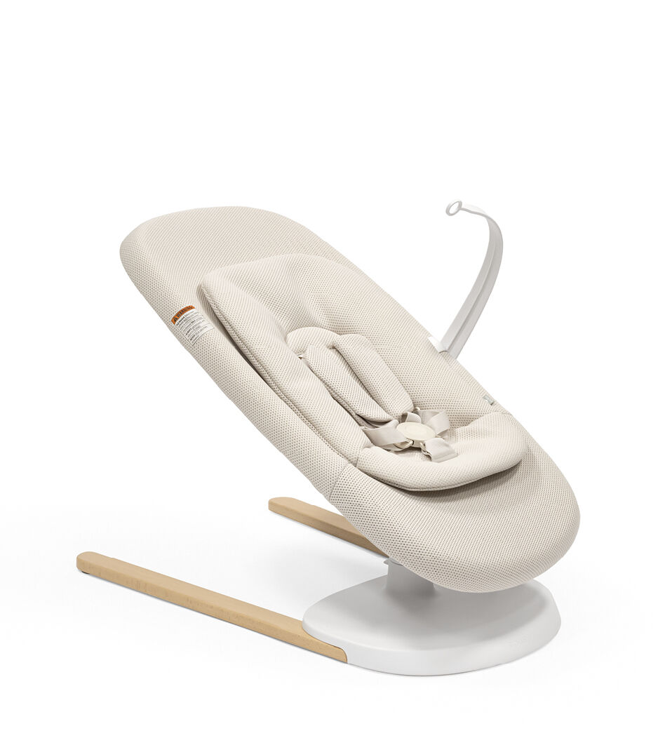 Stokke® Yoga™ Bouncer Light Sand. Low position with inlay. Toy Hanger. US variant.