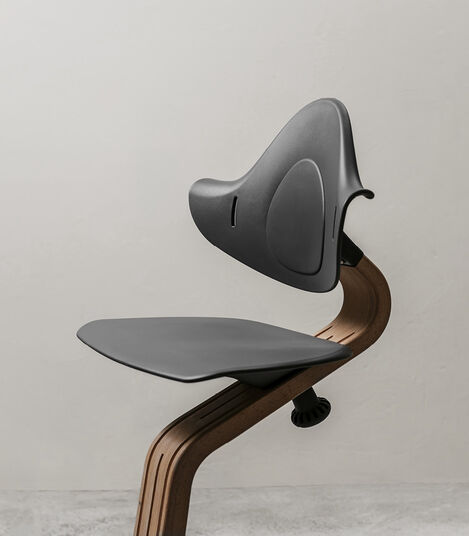 Stokke® Nomi® Chair. Walnut premium wood and Anthracite plastic parts. Styled/detail. view 2