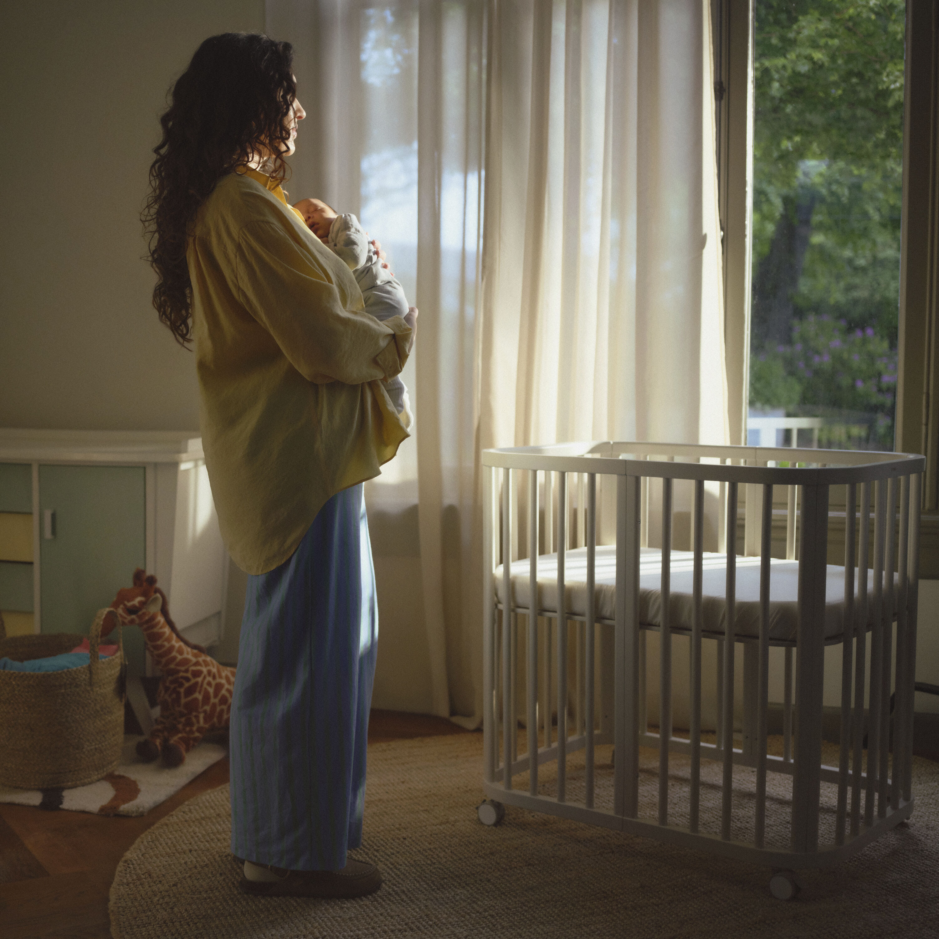 Lifestyle shot of the Stokke® Nighti™ Convertible Cot Bed positioned in a small, beautifully styled modern nursery, with clear space around it and a calm, airy feel, illustrating smart furniture layout planning.