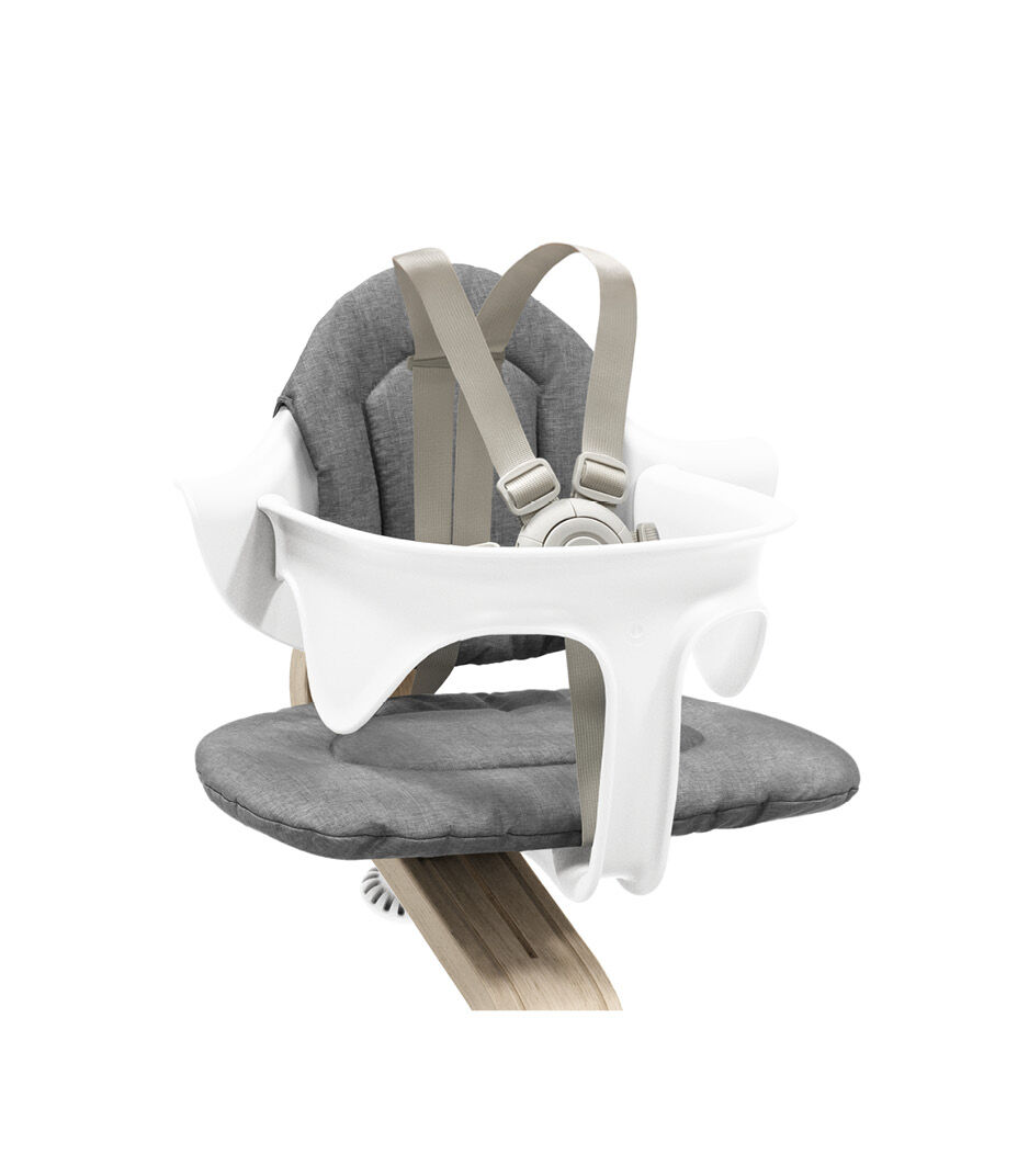 Stokke® Nomi® Chair. Premium Oak wood and White plastic parts. With Baby Set White and Cushion Grey. US variant w/Harness. Close-up.