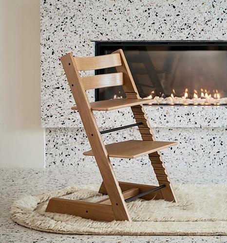 Tripp Trapp chair in color natural in front of a fireplace.