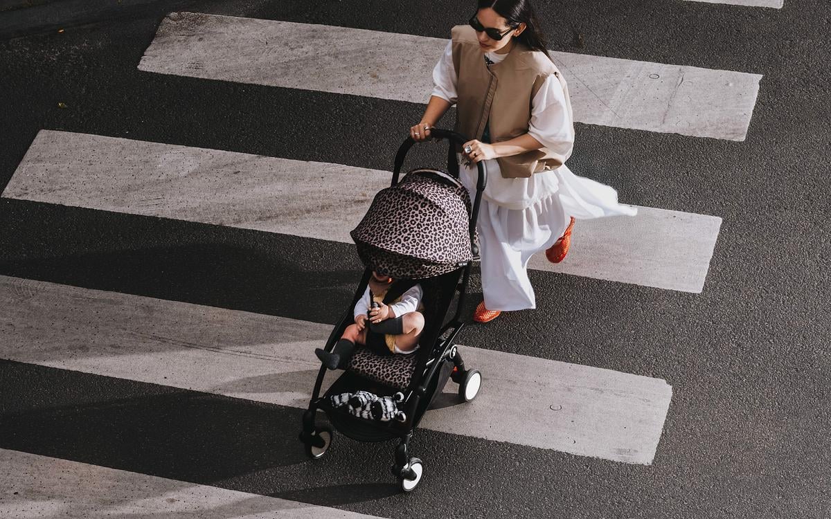 Woman pushing an animal print YOYO stroller on a crosswalk.