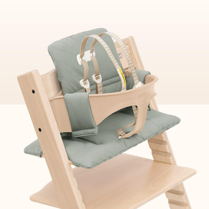 Closeup of natural tripp trapp high chair with natural colored baby set with harness and glacier green cushion.