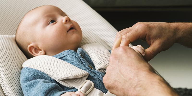 A baby is laying securely on the portable baby bouncer