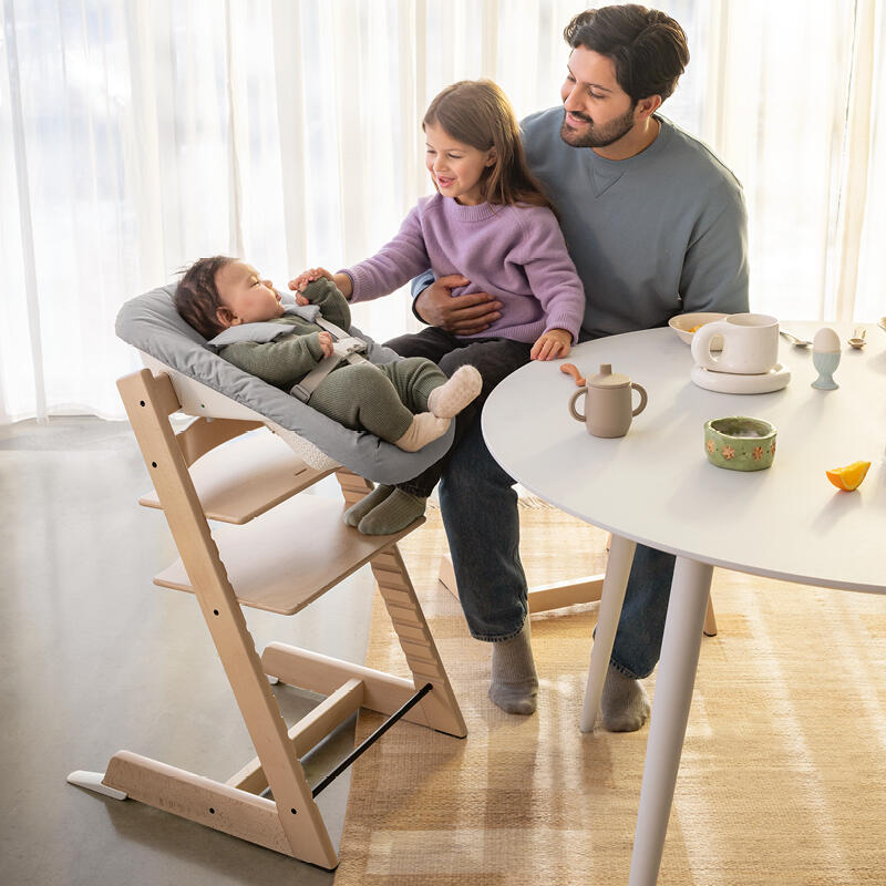 A father with his daughter sitting on his lap and his infant son in the Tripp Trapp newborn bundle high chair.