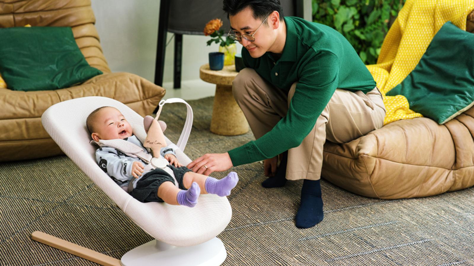 Father watching newborn baby in Yoga bouncer.