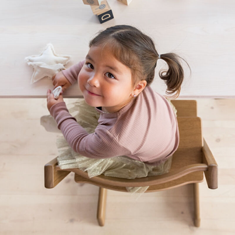 Kid smiling sitting on TT Oak brown chair