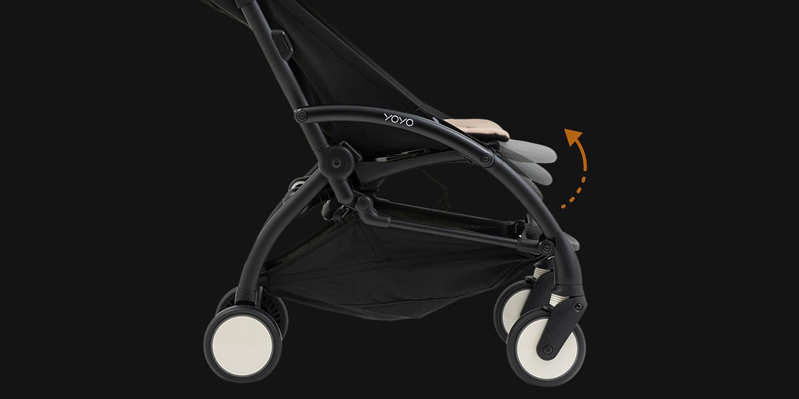 Svart STOKKE YOYO barnvagn med beige säte som visas liggande, indikerat med en orange pil.