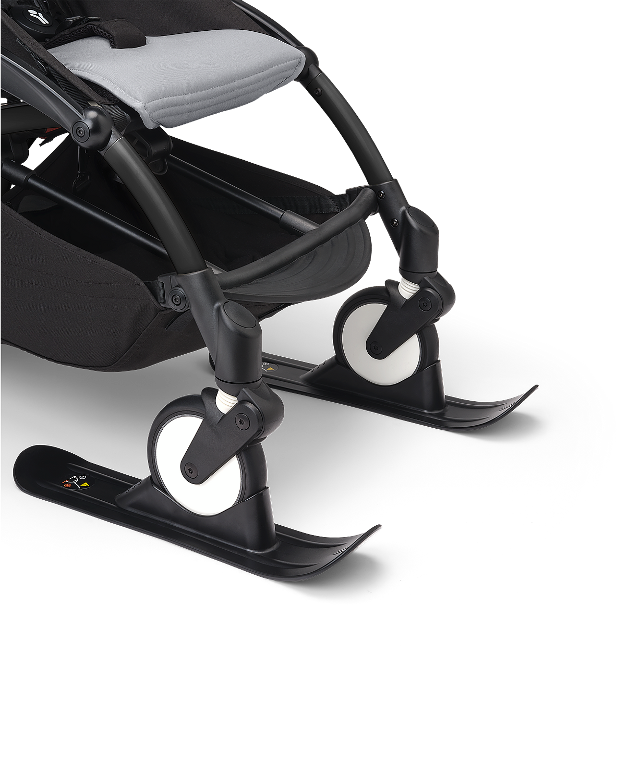 Cochecito STOKKE YOYO con accesorios de esquí negros en sus ruedas delanteras.
