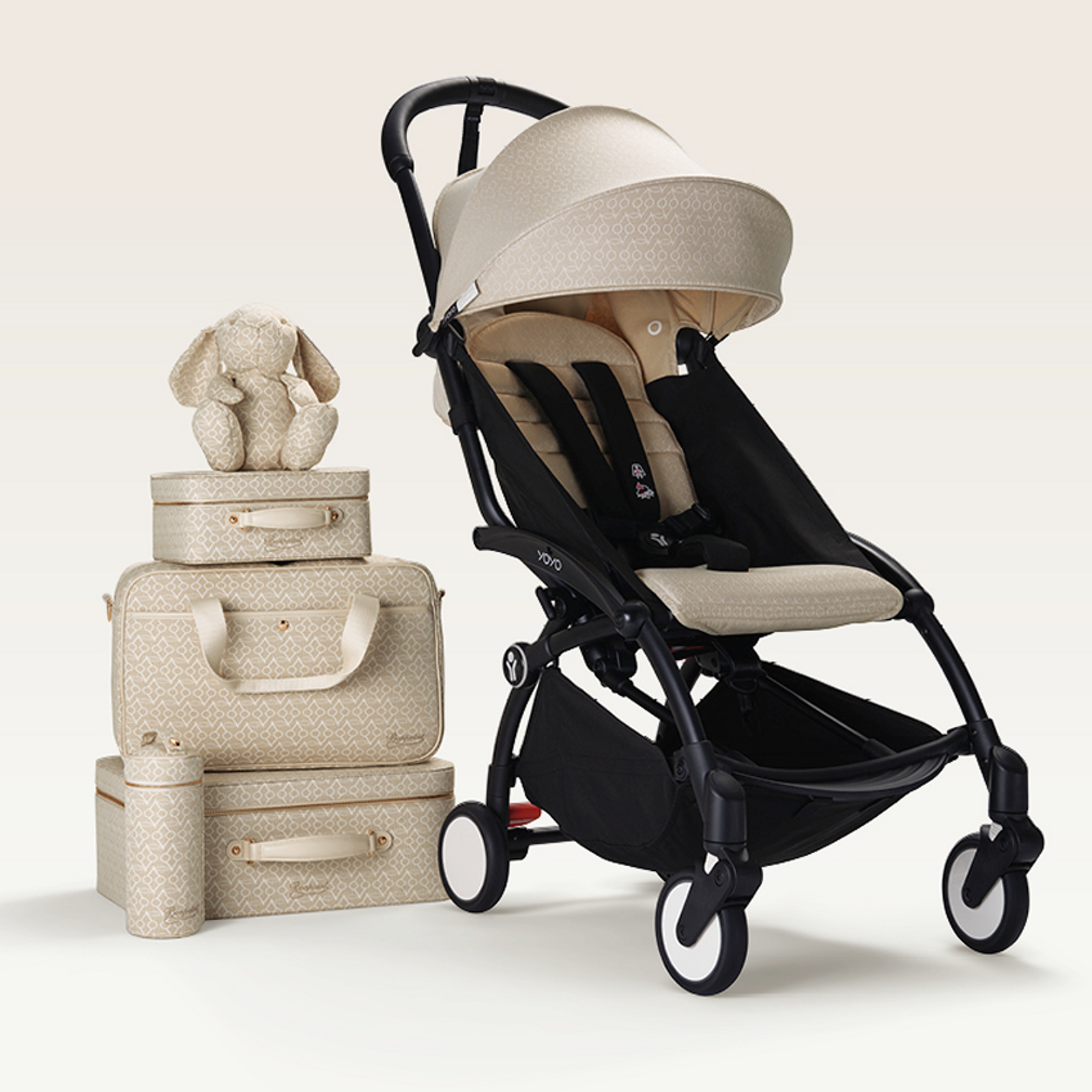 STOKKE YOYO Kinderwagen und passendes beiges gemustertes Gepäckset mit einem Hasenspielzeug.