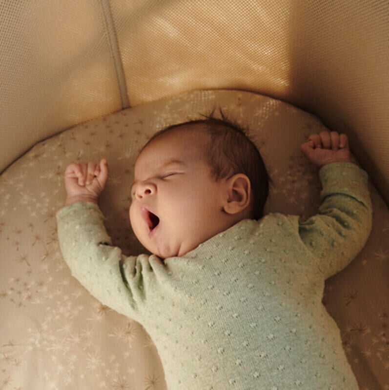 Baby yawning in snoozi bassinet.
