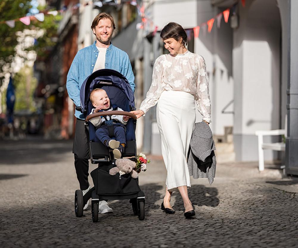 Mom, dad and baby in stroller walking in the street
