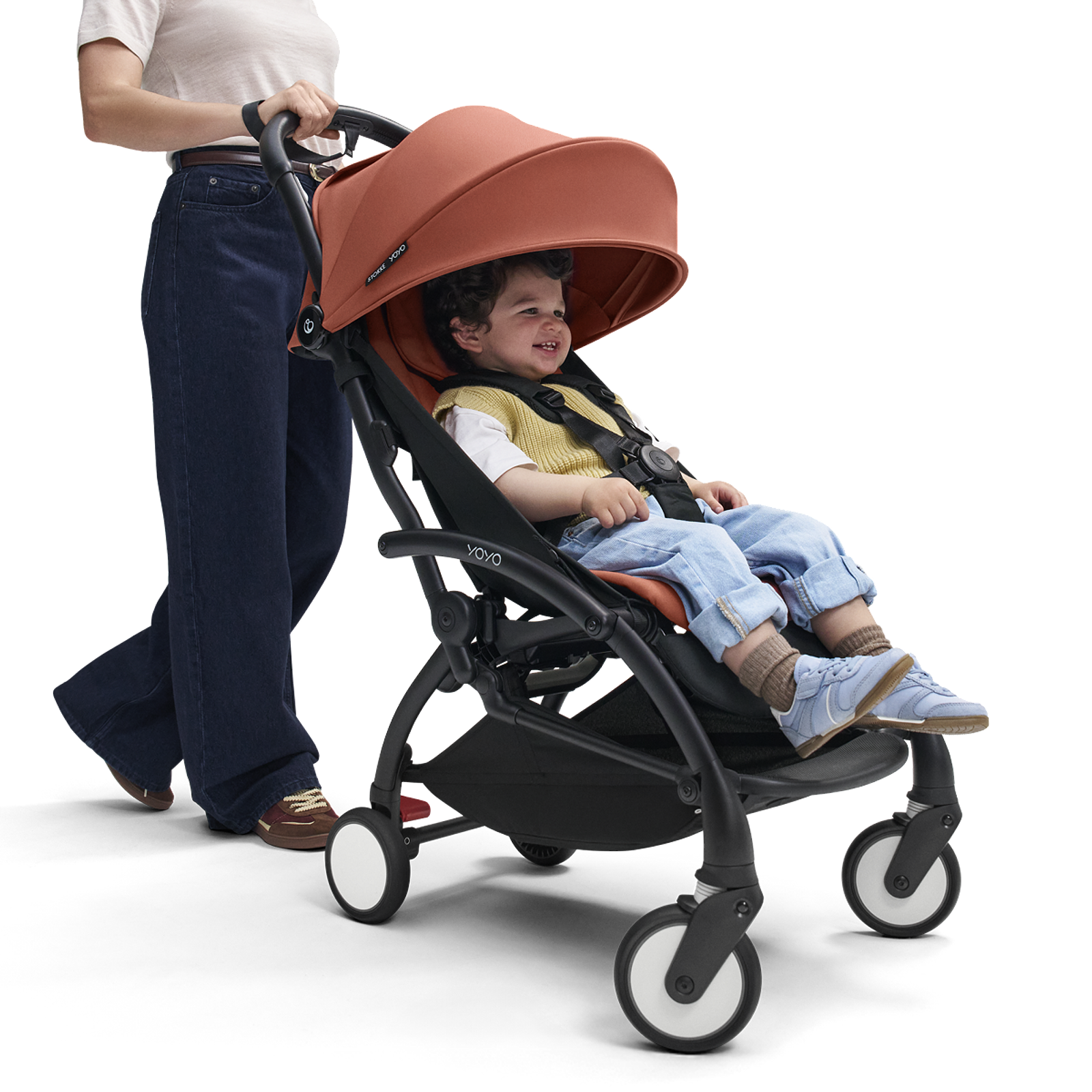 En kvinna skjuter ett glatt barn i en terrakottafärgad STOKKE YOYO barnvagn.