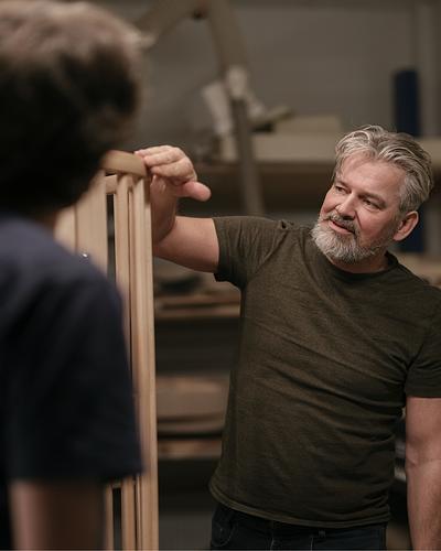 A craftman touching a wooden children's bed.