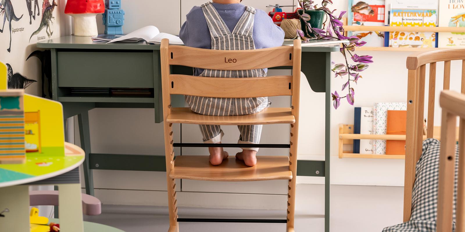 Barn sitter vid ett grönt skrivbord i en personlig Tripp Trapp-stol med 'Leo' ingraverat.