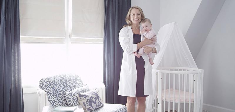 <p>Dr. Levine holding a baby next to the bed</p>