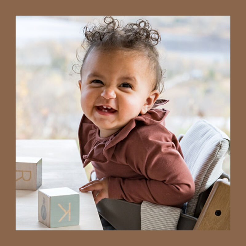 Kid laughing sitting on TT Oak brown chair