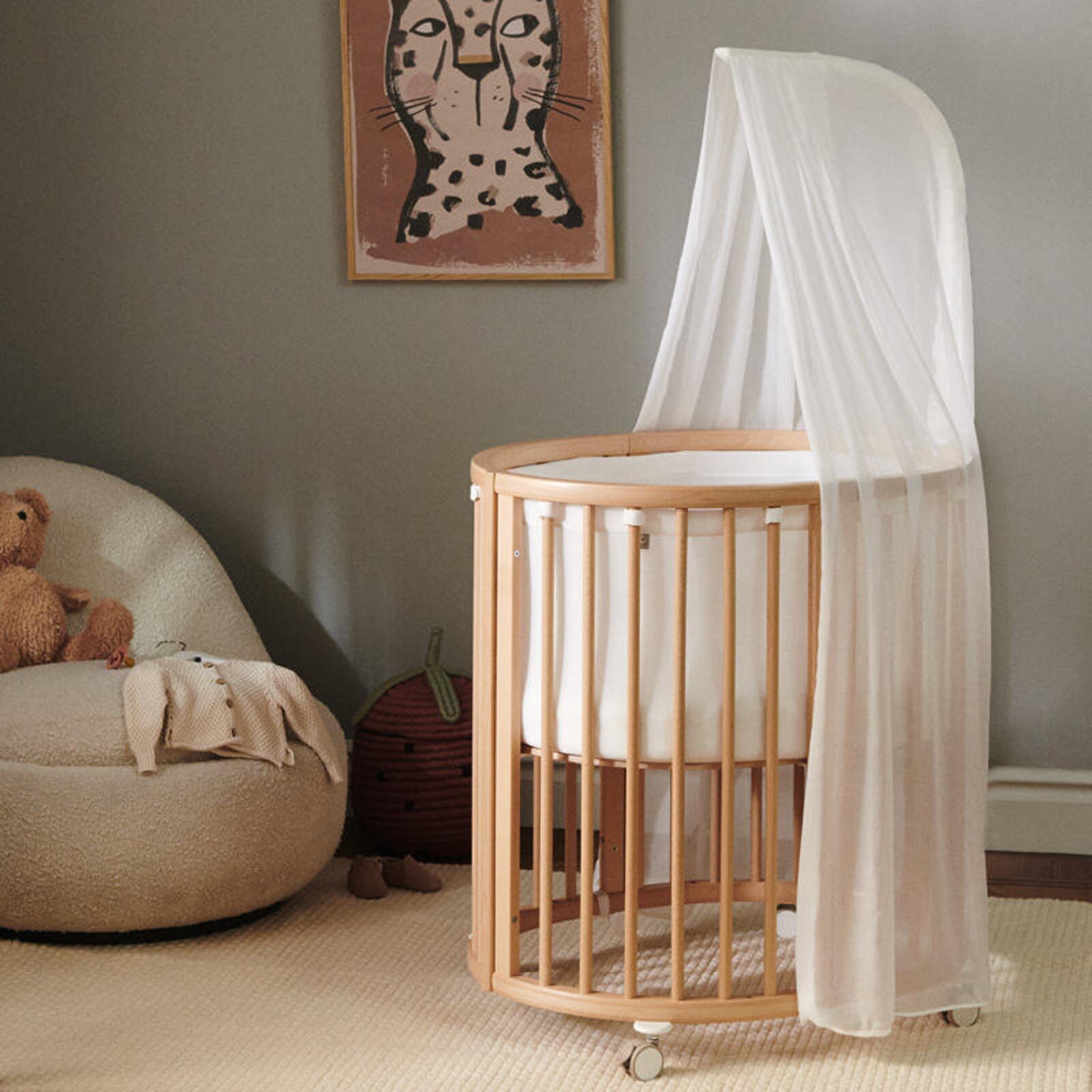 Sleepi Mini crib with canopy and liner in baby nursery.