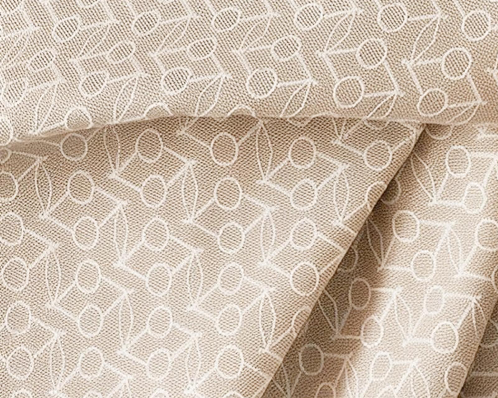 Light brown textured fabric with a white embroidered pattern of circles and leaves.
